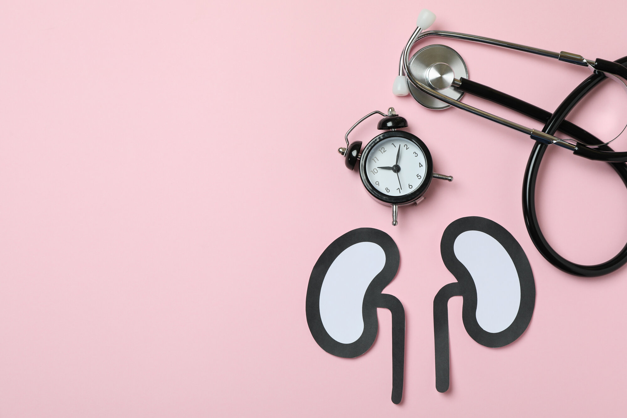 nieren-gesundheit.jpg Papierfiguren von Nieren auf einem rosa Hintergrund, daneben eine Armbanduhr und ein Stethoskop.