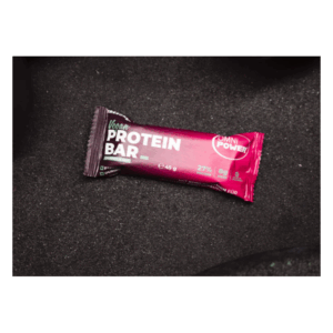 Eine vegane Proteinriegel-Verpackung in lila mit den Angaben zu Nährstoffen, auf dunklem Hintergrund.